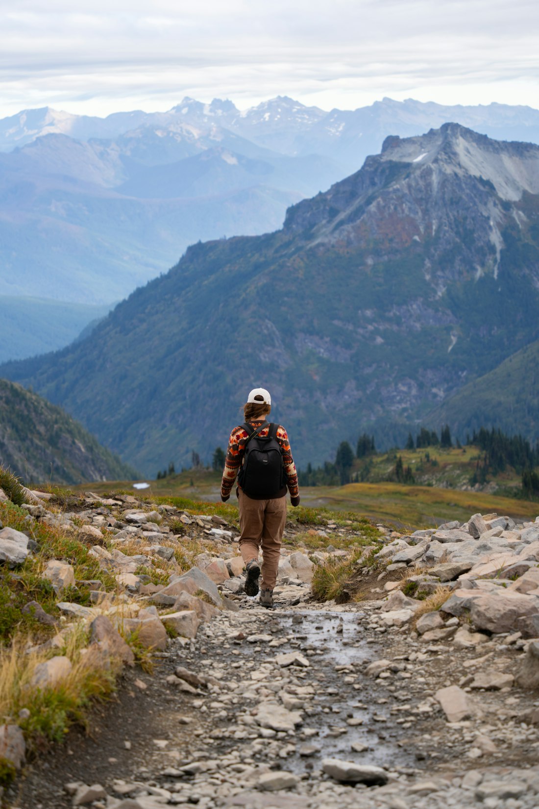 Hiker with daypack on a misty Cascade ridge trail